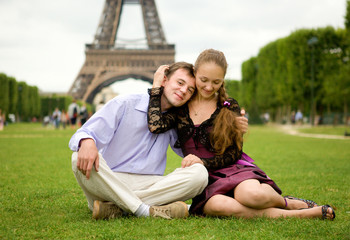 Happy romantic couple in Paris, sitting on grass by the Eiffel T