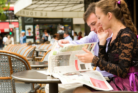Romantic couple in Paris, reading newspaper in cafe
