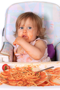 Messy baby girl eating spaghetti