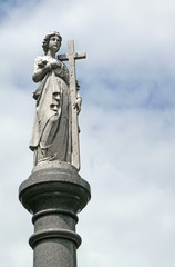 Female figure cemetary statue with cross atop pillar