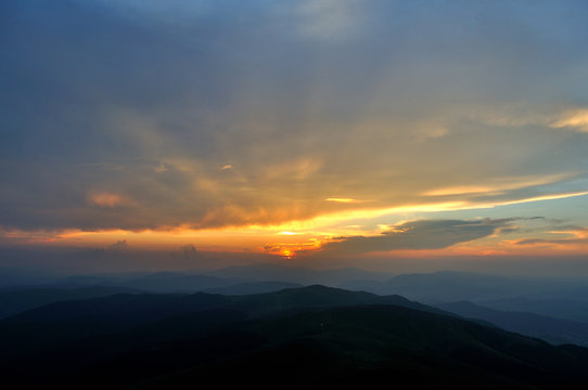 Setting sun over blue mountains