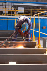Naklejka premium worker weld metal in factory and sparks