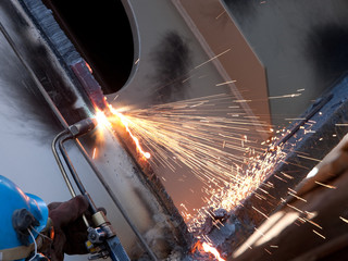 worker inside factory cut metal using blowtorch