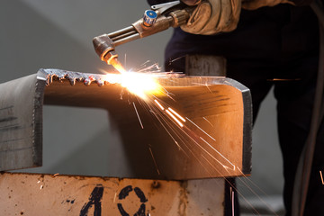 worker inside factory cut metal using blowtorch