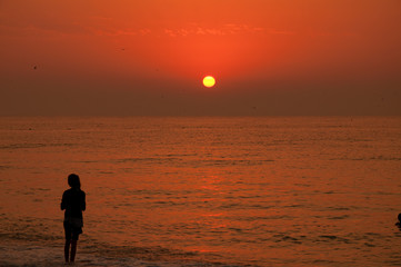Young girl watching the sunset at the sea