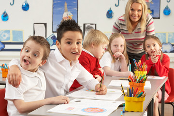 Fototapeta premium Group Of Primary Schoolchildren And Teacher Working At Desks In