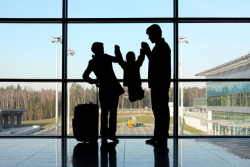 Obraz premium silhouette of parents holding child standing near window