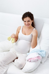 Beatiful pregnant woman choosing baby's clothes