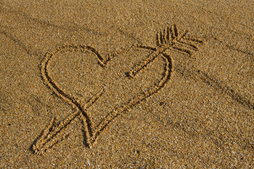 Heart with arrow in the sand.