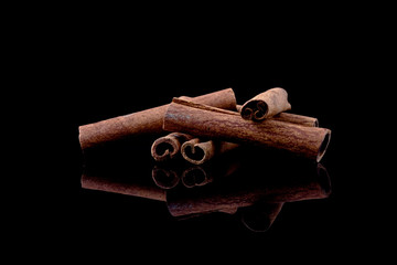 cinnamon sticks on black background with reflection