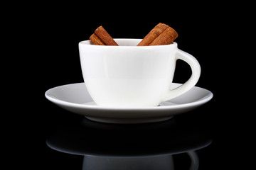 cinnamon sticks in a white cup on black background