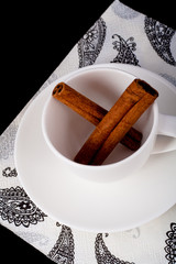 cinnamon sticks in a white cup standing on a napkin