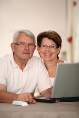 Senior couple at home with laptop computer