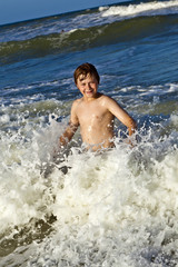 young boy enjoys the waves of the blue sea