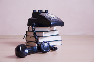 stack of books with vintage telephone on top