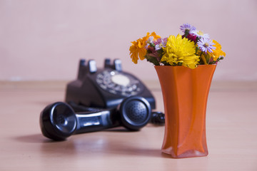 vase with colored flowers and vintage telephone