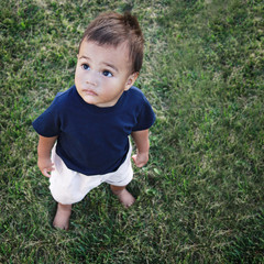 Small baby standing on the grass looking up