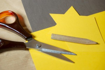 gelber Stern auf braunem Papier, Schere, Stift
