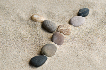 Fototapeta na wymiar lettre Y en galets zen dans le sable