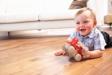 Young Boy Playing With Wooden Toy Car At Home