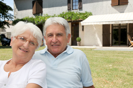 Senior couple sitting in front of a house