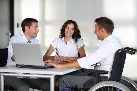 Businessman in wheelchair working in the office with colleagues