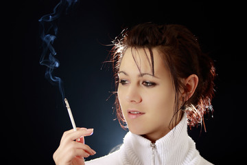 Obraz premium Contemplation and Elegance: A Beautiful Woman Smoking a Cigarette against an Isolated Dark Background