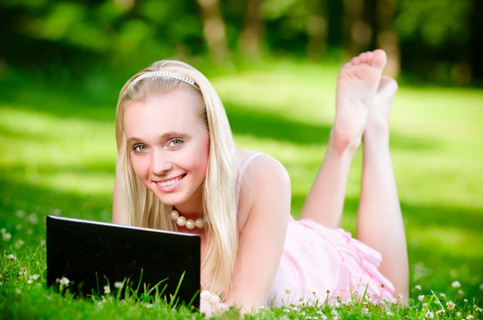 Beautiful blonde on the grass with laptop