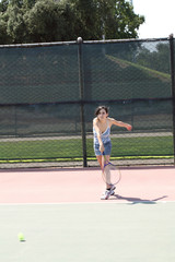 young hispanic teen girl swinging tennis racket