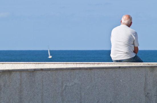 Anciano sentado contemplando el mar