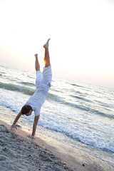 Young man doing cartwheels on the beach