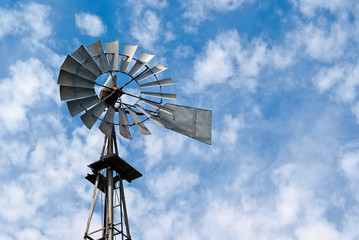 Old Metal Water-pump Windmill Against Cloudy Blue Sky