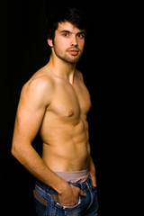 Fototapeta premium Young man with atletic body on black background
