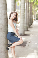 Attractive young fashion model leaning on a tree and smiling