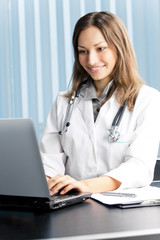 Happy doctor or nurse with laptop at office