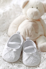 Baby girl shoes and teddy bear on white background