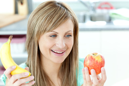 Jolly young woman holding an appke and a banana