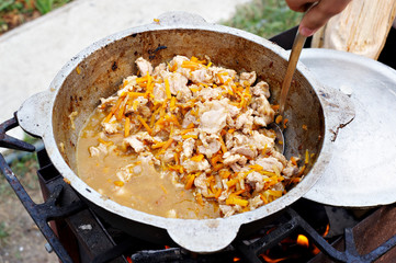 Preparation pilaf in the cauldron on fire