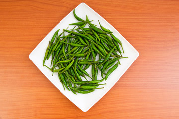 Hot peppers in the plate on wooden table