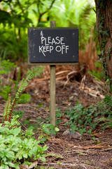 please keep off sign against pretty woodland scenery 