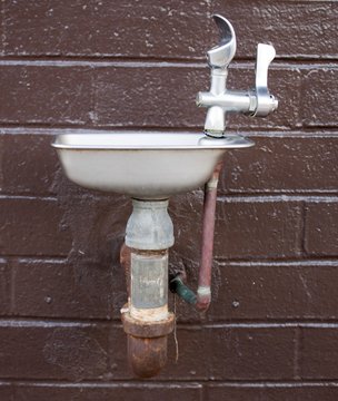 school water fountain with a brick background