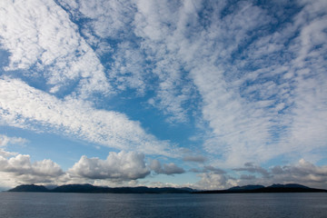panorama with a lot of sky and clouds, the sea blue and mountains in the background in a summer day in Norway