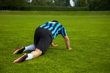 Fußballspieler kriecht auf dem Boden