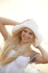 Beautiful young blonde girl in hat on the beach