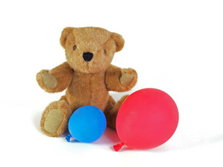 Teddy Bear holdind a blue and red balloon.