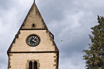 Fototapeta na wymiar Kirchturm mit einelnen Luftballon