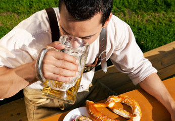 Mann in Lederhosen trinkt Bier
