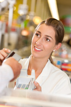 Kassiererin im Supermarkt nimmt Kreditkarte