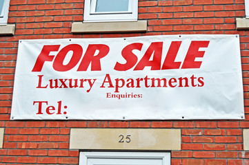 Notice on a red brick house displaying For sale  Luxury Apartments  space to add your own telephone...