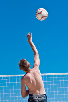 young boy playing volleyball on beach